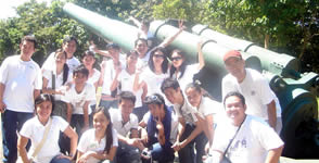 Students and faculty pose behind one of the big cannons in the island.