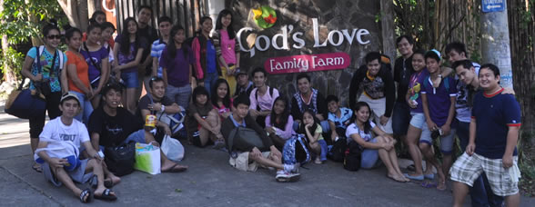 Students pose in front of God's Love Farm Logo Facade.